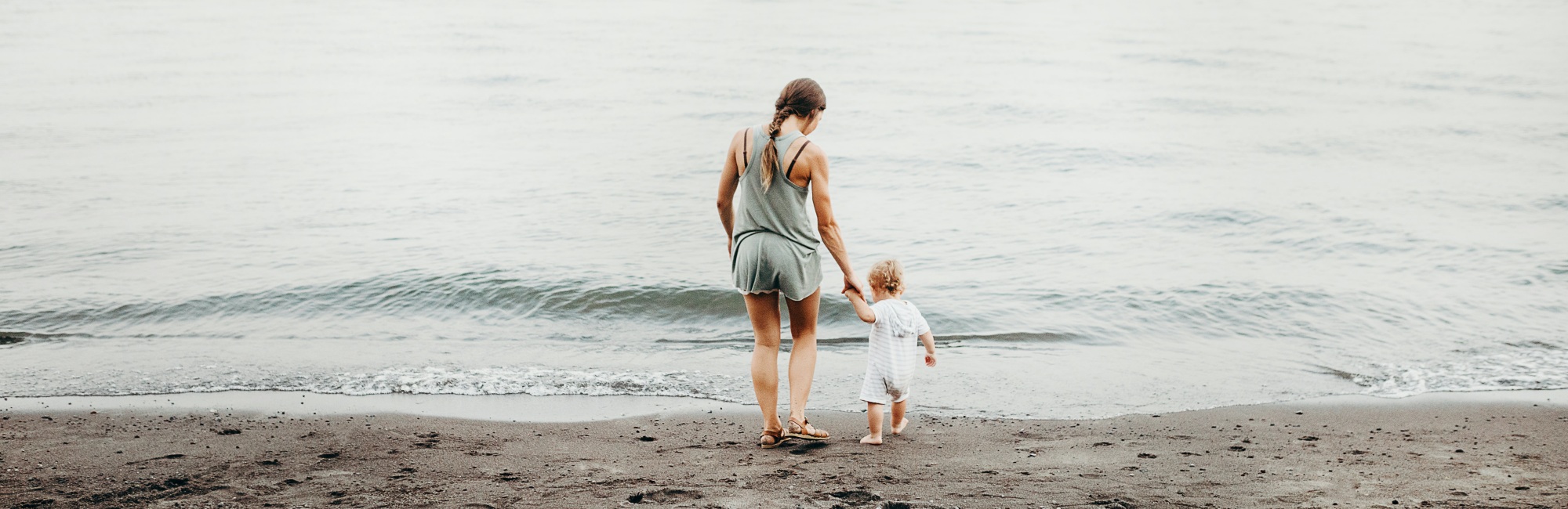 mother and child playing by ocean water's edge