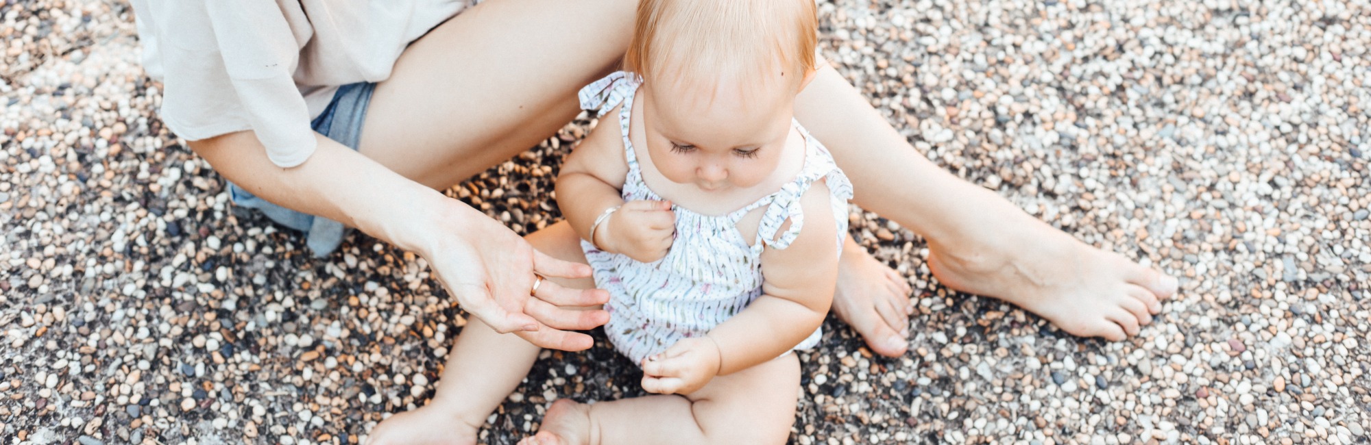 adult and caucasian baby sitting outside on a path